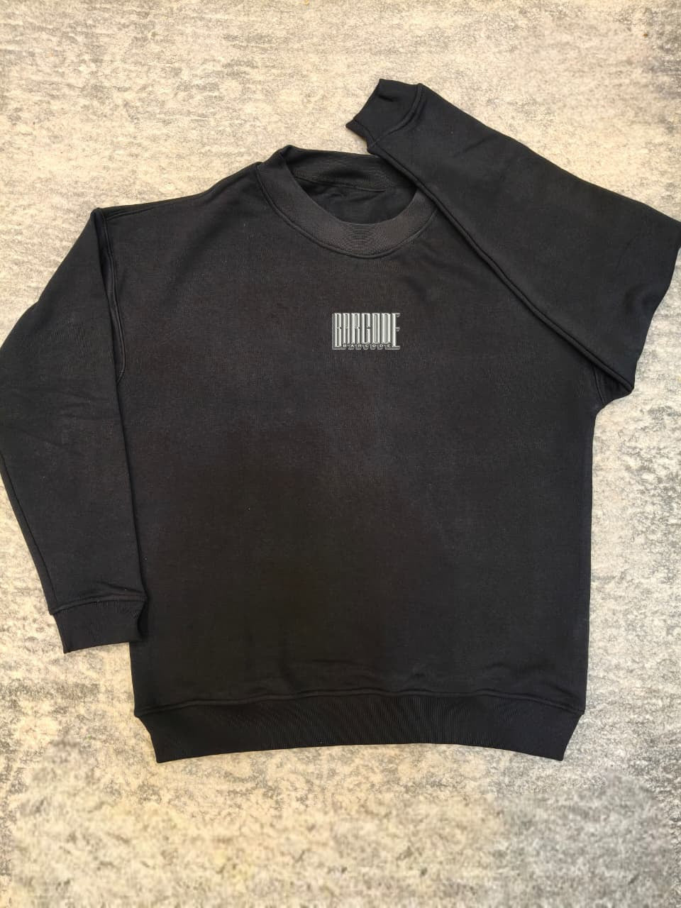 Black sweatshirt with a barcode design on a textured surface